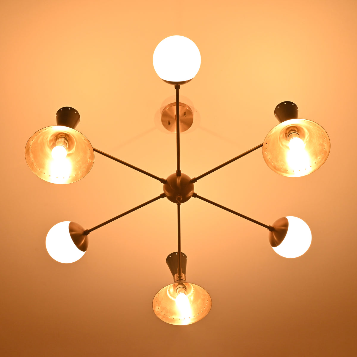 Bottom view of a 9-light brass chandelier featuring illuminated cone shades and opal globes arranged in a radial layout.