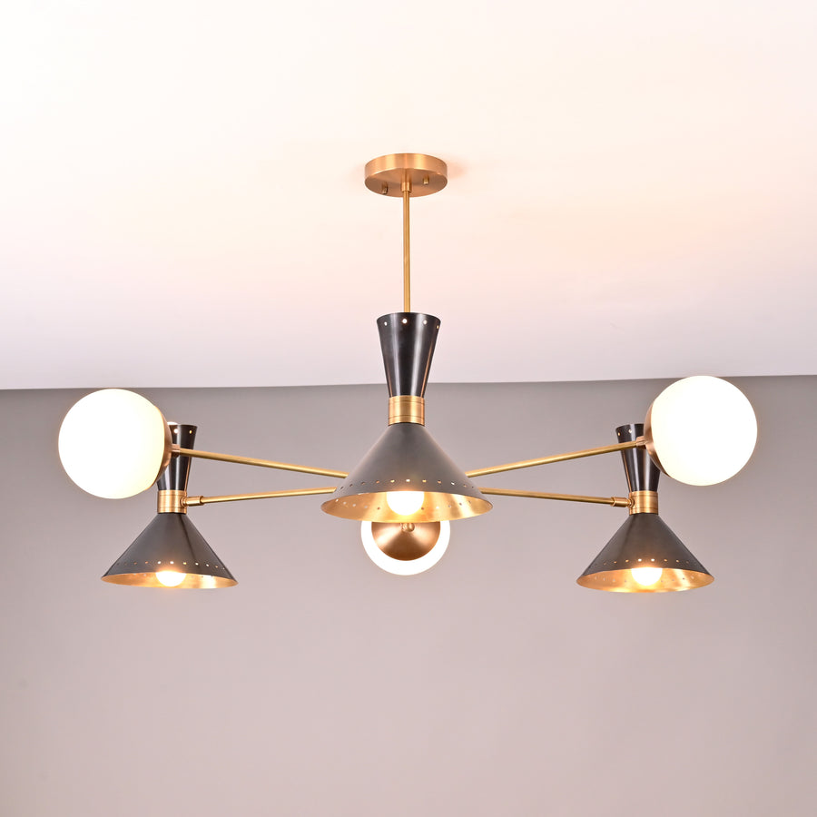 Front view of a 9-light brass chandelier featuring perforated cone shades and opal globes in a modern mid-century design.