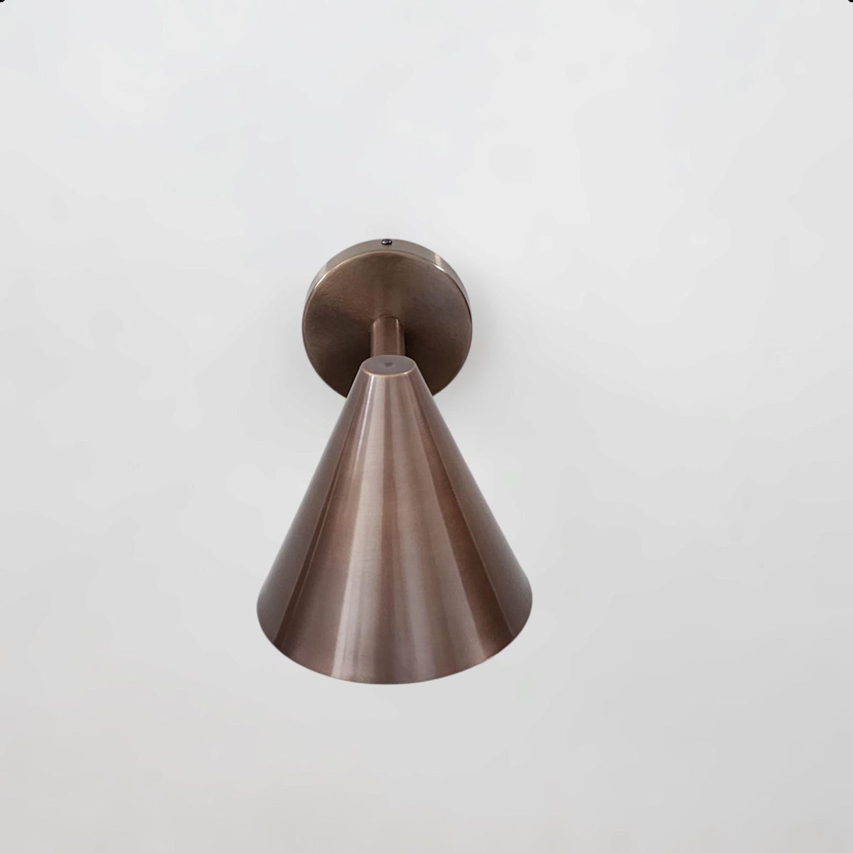 Front view of antique brass cone wall light showcasing sleek geometry and precision craftsmanship by Brass Leaf Studio.