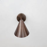 Front view of antique brass cone wall light showcasing sleek geometry and precision craftsmanship by Brass Leaf Studio.