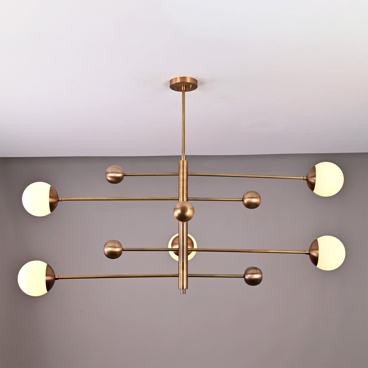 Brass Leaf Studio Aurelia globe chandelier featuring a 5 light linear design with solid brass construction and opal glass shades