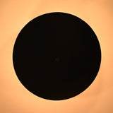 Bottom view of a matte black bowl ceiling light casting a circular warm halo of light on the ceiling.