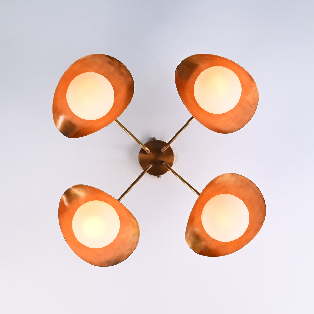 Bottom view of brass flush mount ceiling light showing four evenly spaced opal globe diffusers