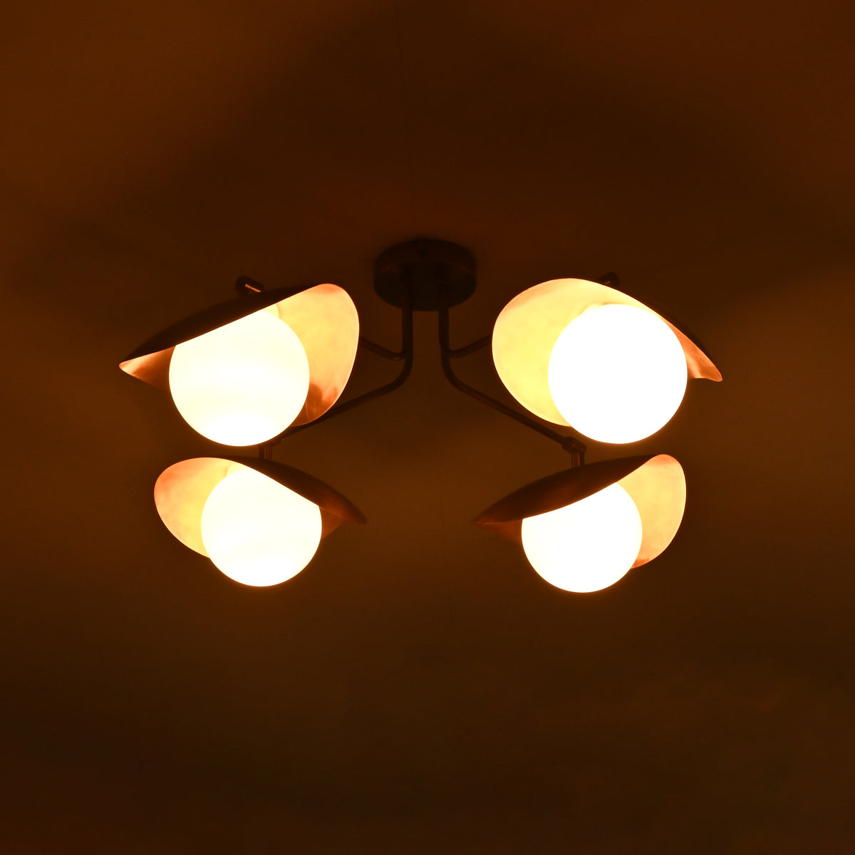 Angled night view of handcrafted brass flush mount ceiling fixture with glowing opal globes