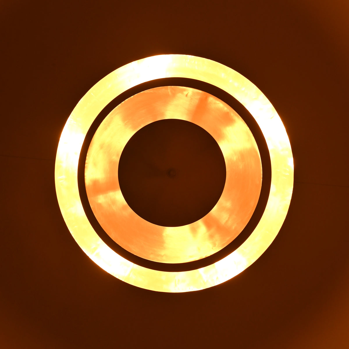 Glowing circular reflection of handcrafted brass chandelier producing ambient golden light