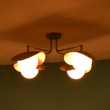 Side perspective of brass ceiling light at night highlighting curved bowl shades and warm illumination