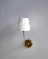 Elegant handcrafted brass wall lamp with white pleated shade, minimalist design by Brass Leaf Studio.