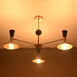 Illuminated industrial brass cone shade chandelier showing warm glowing perforated shades by Brass Leaf Studio.