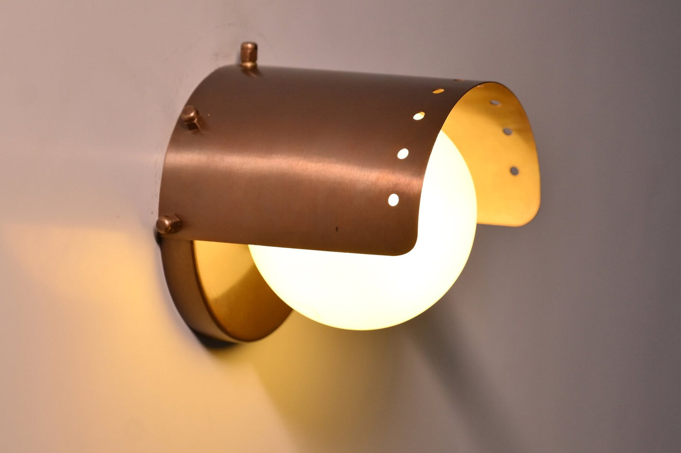 Handcrafted industrial brass wall light with curved brushed brass shade and glowing globe by Brass Leaf Studio