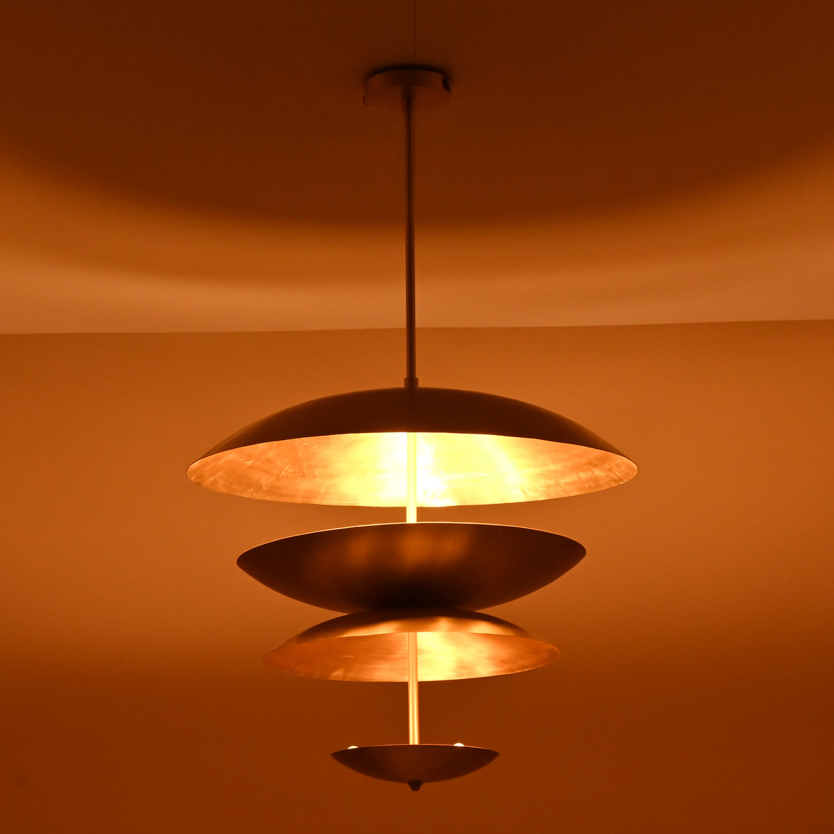 Minimalist three-layer brass pendant chandelier emitting warm light and soft golden ambiance