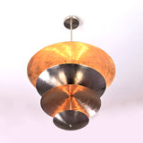 Bottom view of a sculptural tiered disc chandelier, showcasing concentric reflective brass discs illuminated from within.