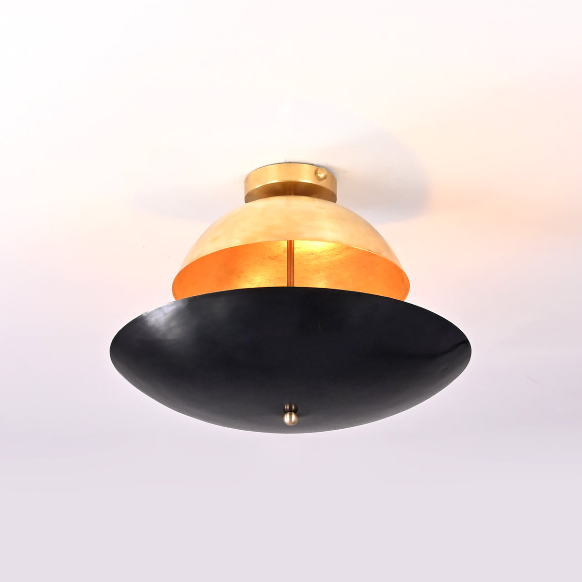 Artistic sculptural flushmount chandelier with warm inner glow, featuring a brass dome top and matte black bowl bottom.