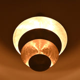 Warm ambient view of a tiered bowl-disc chandelier featuring layered sculptural metal shades by Brass Leaf Studio.
