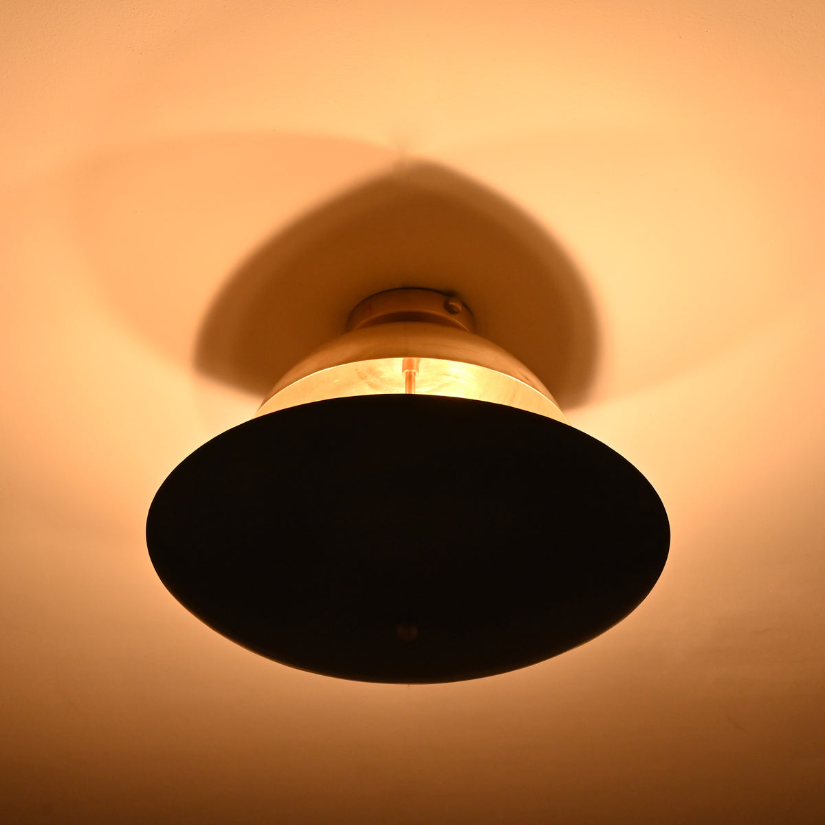 Two-tone dome ceiling light with warm golden ambient illumination creating soft shadows and sculptural ceiling effects.