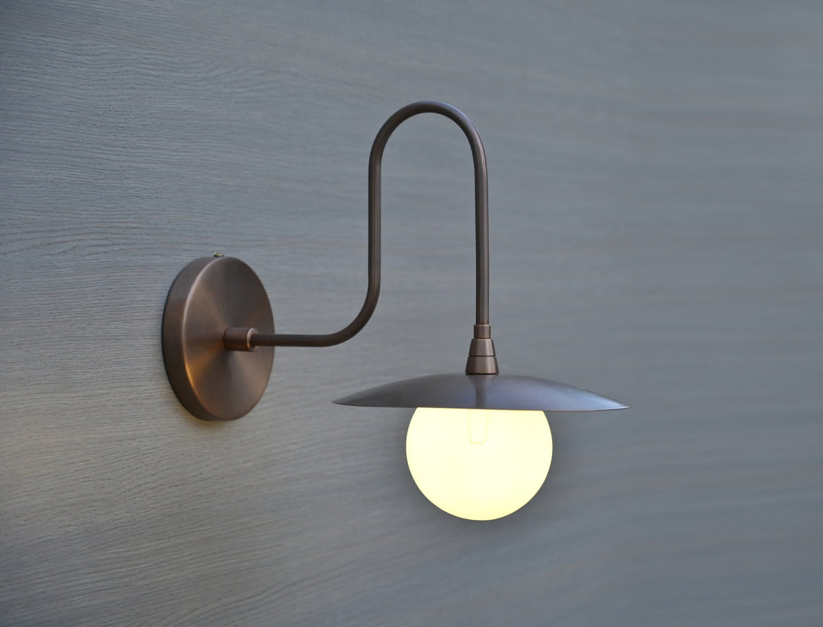 Modern brass wall sconce by Brass Leaf Studio featuring a globe diffuser and minimalist industrial design.