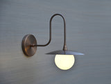 Modern brass wall sconce by Brass Leaf Studio featuring a globe diffuser and minimalist industrial design.