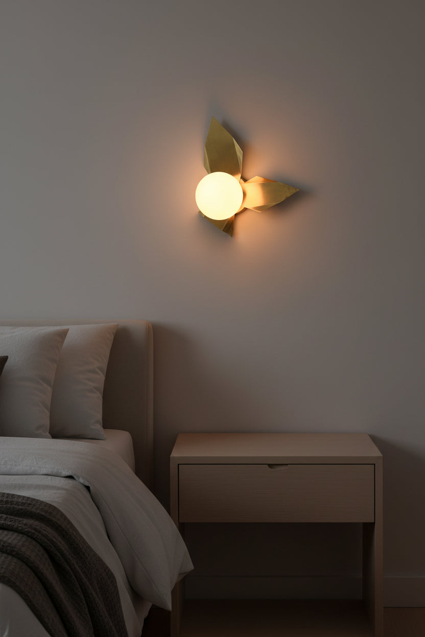 Brass leaves glass globe wall sconce shown from front with artistic folded brass panels and soft warm light