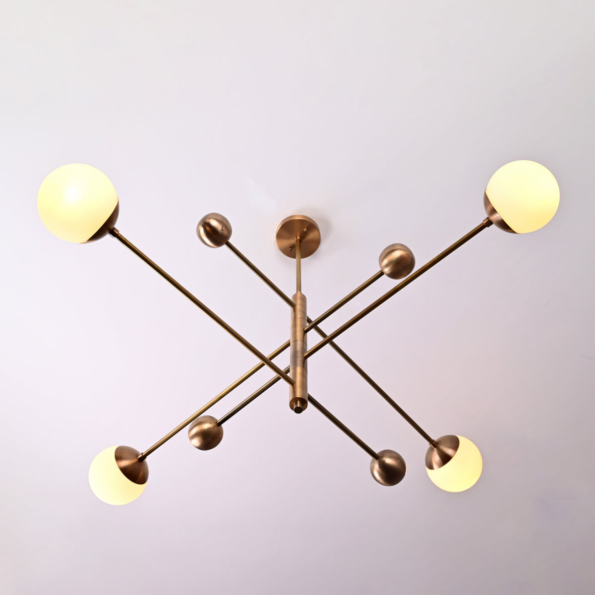 Top view of 4-light solid brass linear chandelier with opal glass globes in brushed brass finish.