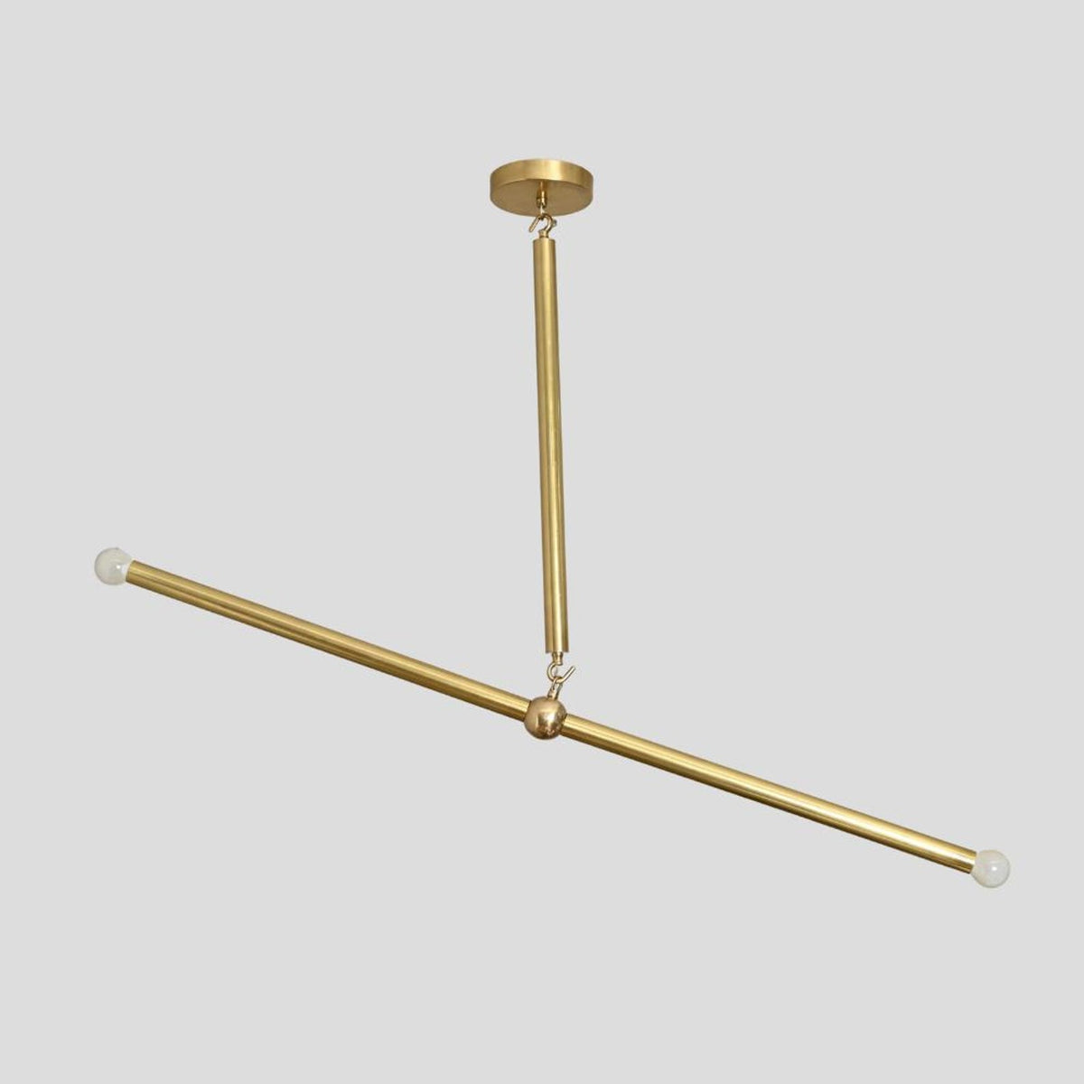 Diagonal view of solid brass linear chandelier with two bulbs on each end, modern industrial ceiling light handmade by Brass Leaf Studio.