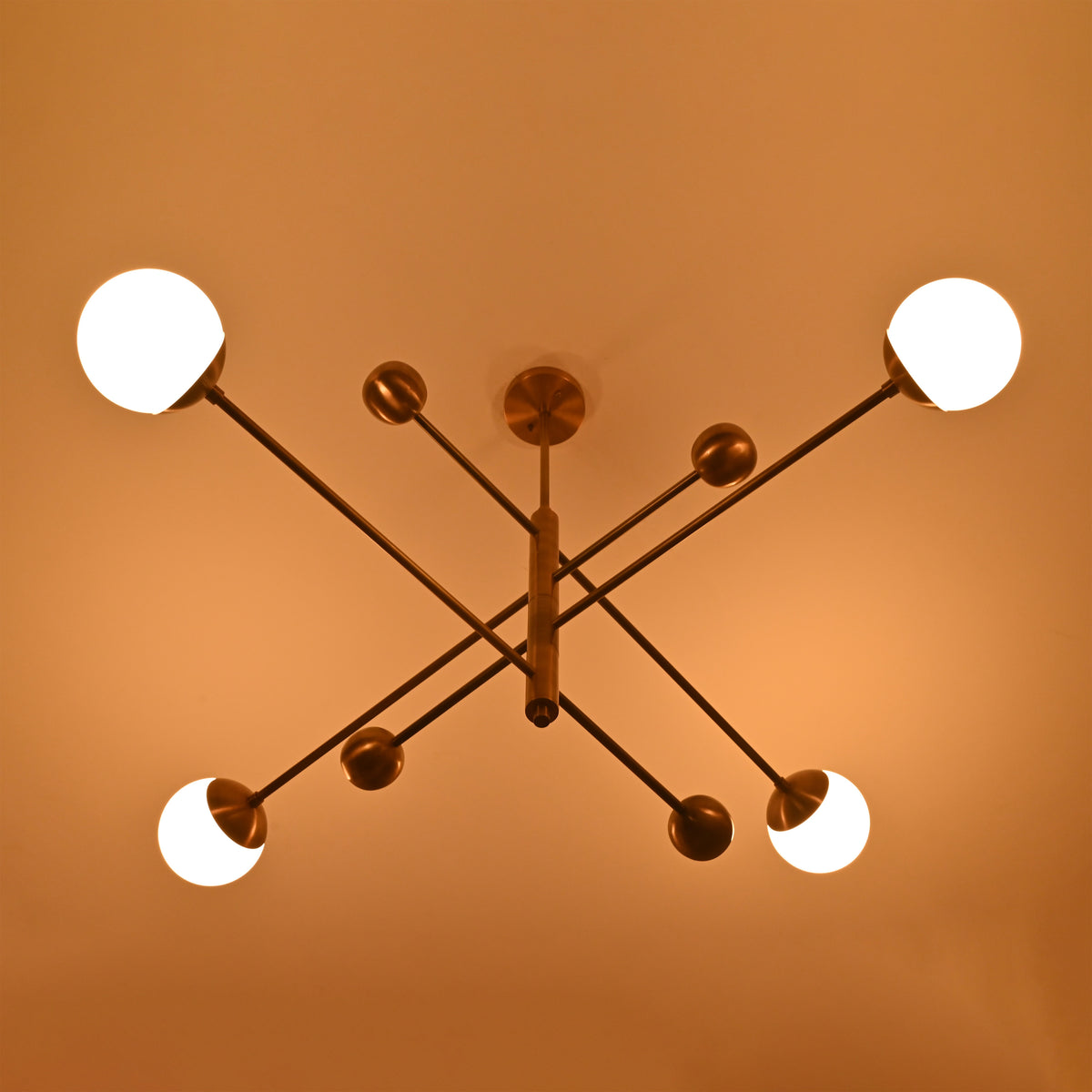 Top view of brass chandelier illuminated in warm ambient light with opal glass globes.