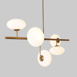 Side view of a handcrafted brass linear chandelier with five milky glass globes, showcasing balanced proportions and minimalist industrial style.