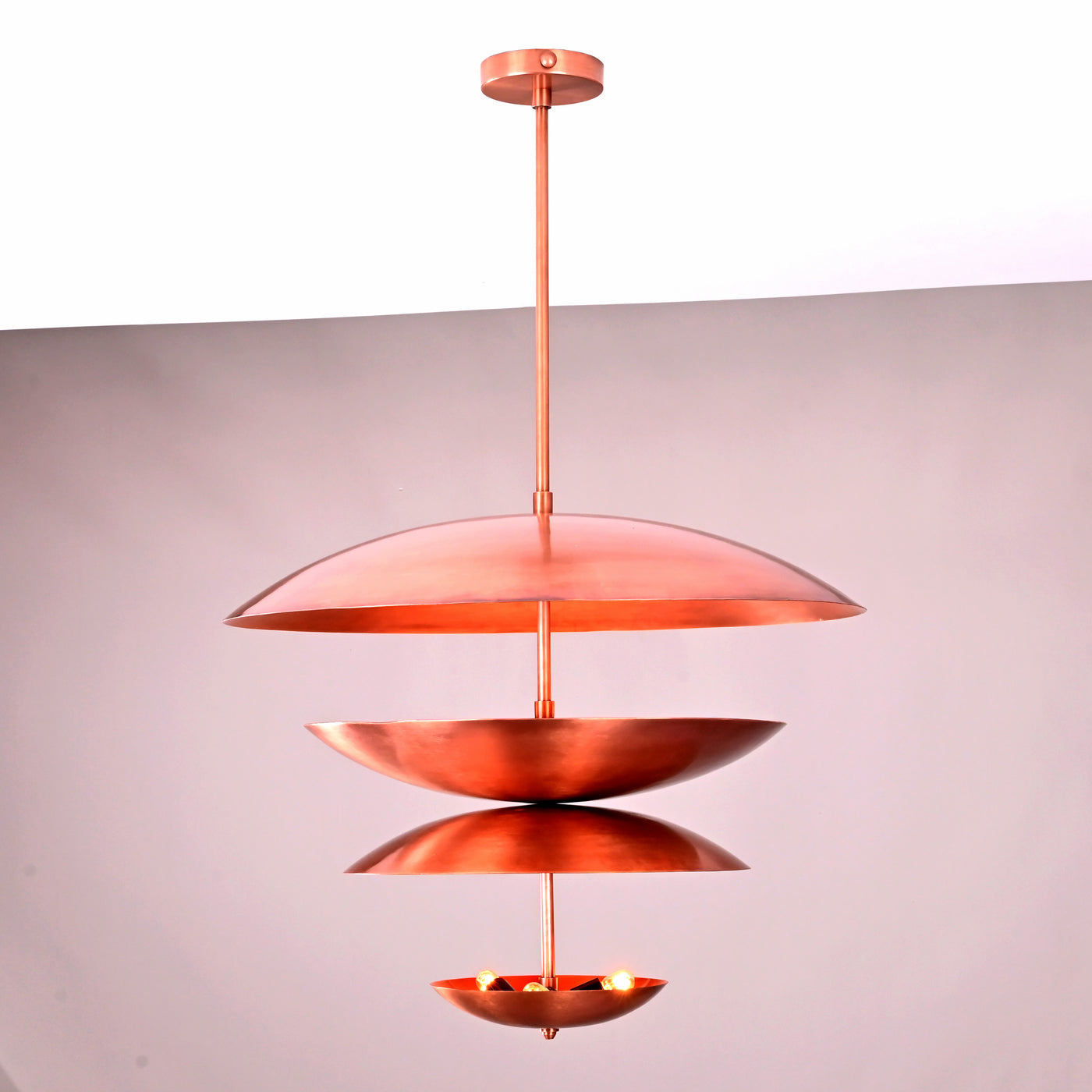 Studio photograph of a copper-finish multi-tier bowl-shaped chandelier with indirect uplighting, crafted in solid brass by Brass Leaf Studio.