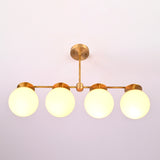 Close-up of opal glass globe shades on solid brass linear chandelier, highlighting warm diffused illumination.