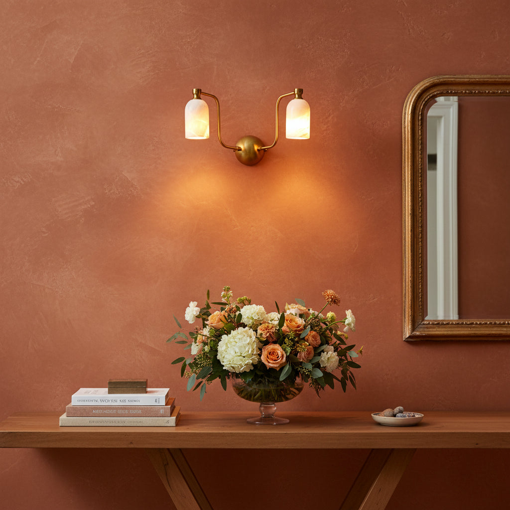 Brass patina vanity wall sconce with two glowing alabaster shades and soft warm bathroom lighting