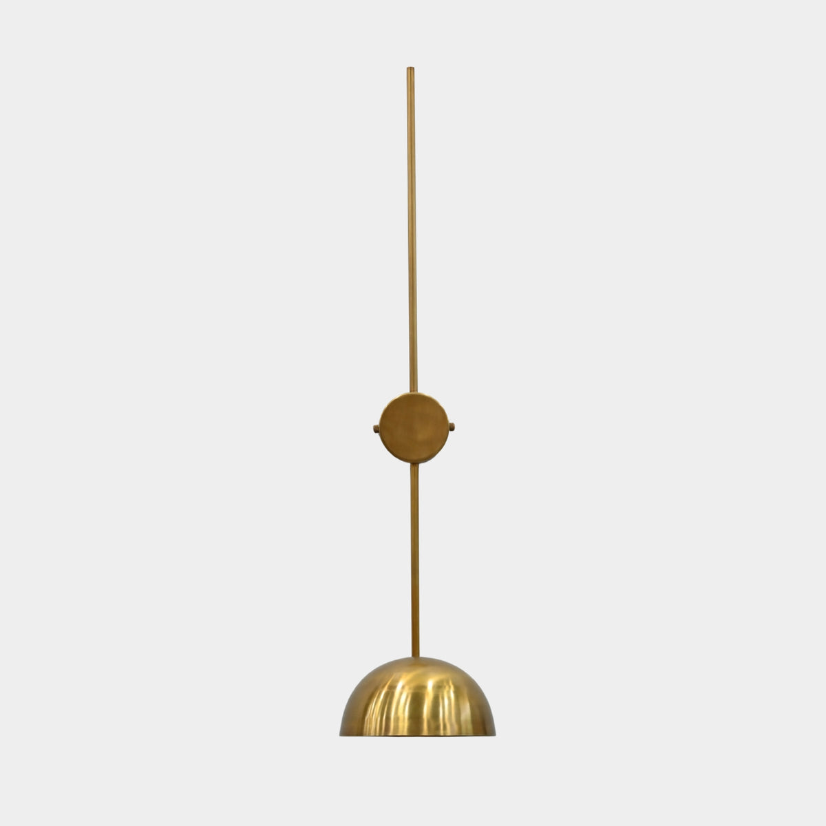 Brass patina bowl wall sconce closeup showing solid brass shade, slim wall stem, and warm interior glow