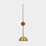 Brass patina bowl wall sconce closeup showing solid brass shade, slim wall stem, and warm interior glow