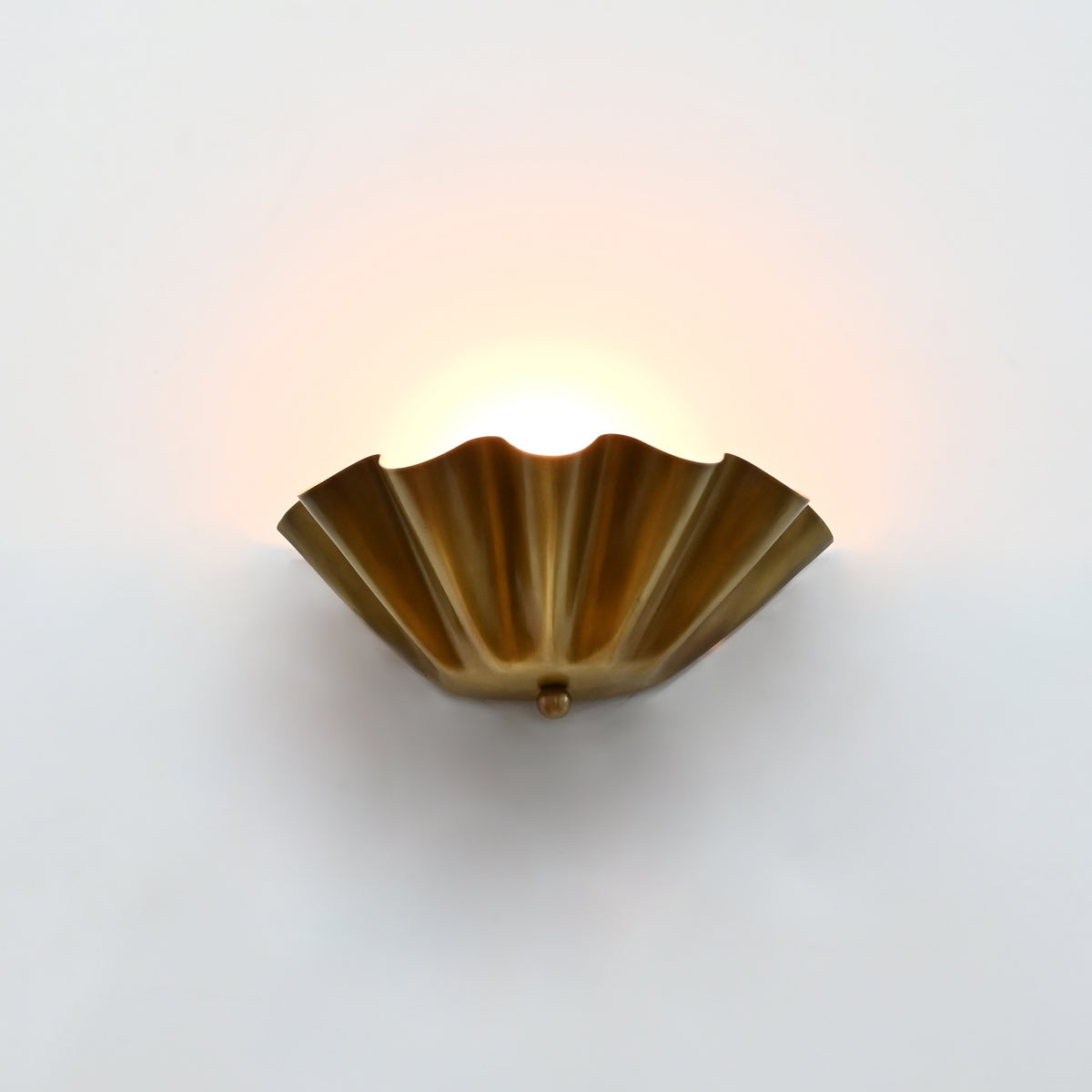 Brass patina ruffled wall light with sculptural fluted bowl shade creating soft ambient wall lighting
