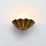 Brass patina ruffled wall light with sculptural fluted bowl shade creating soft ambient wall lighting