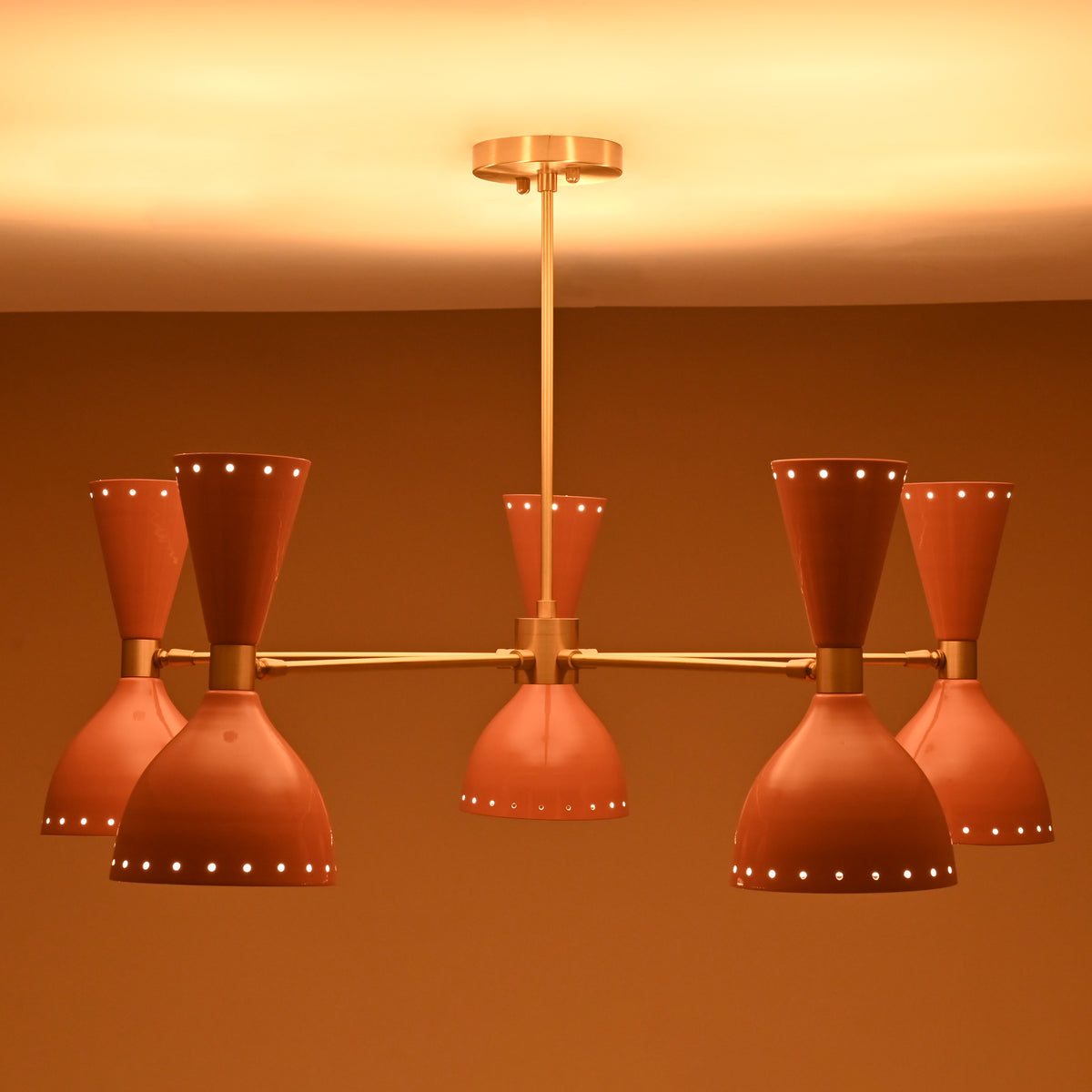 Soft light glowing from six peach brass shades of handmade chandelier