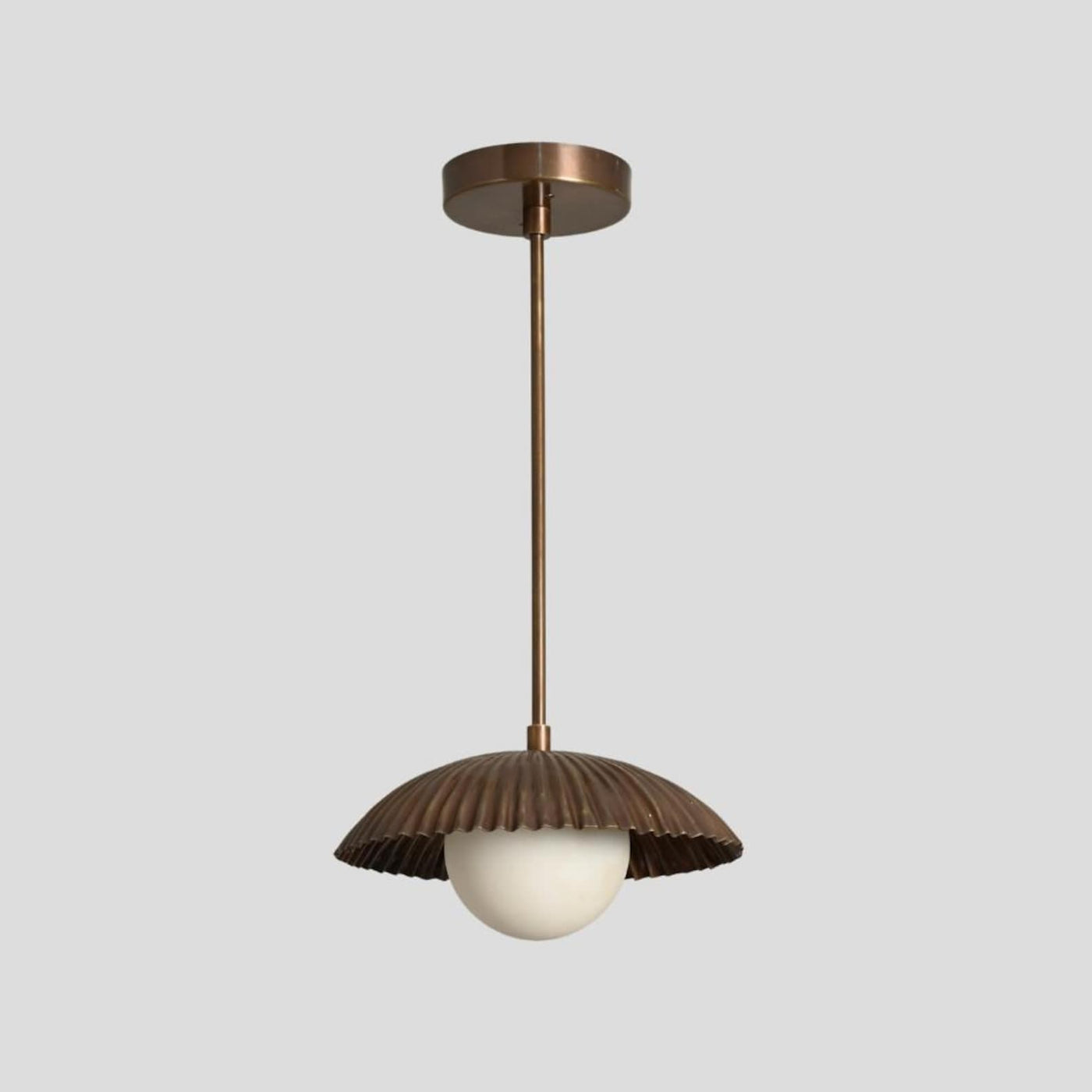 Handmade brass pendant light with dome shade and opal globe bulb, designed by Brass Leaf Studio for modern and industrial interiors.