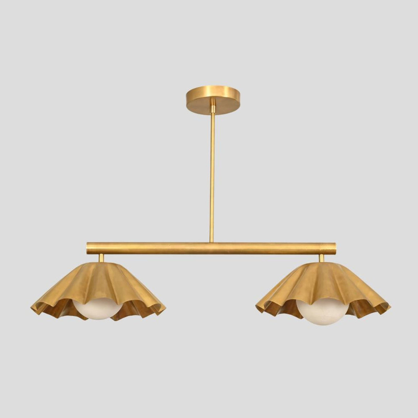 Brass chandelier with two ruffle-edged shades and globe lights, handcrafted pendant for dining rooms and boutique interiors.