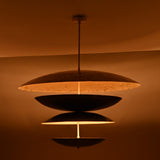 Evening glow of brass layered disc chandelier with multi-tiered bowl shades creating soft diffused light and dramatic ambience.
