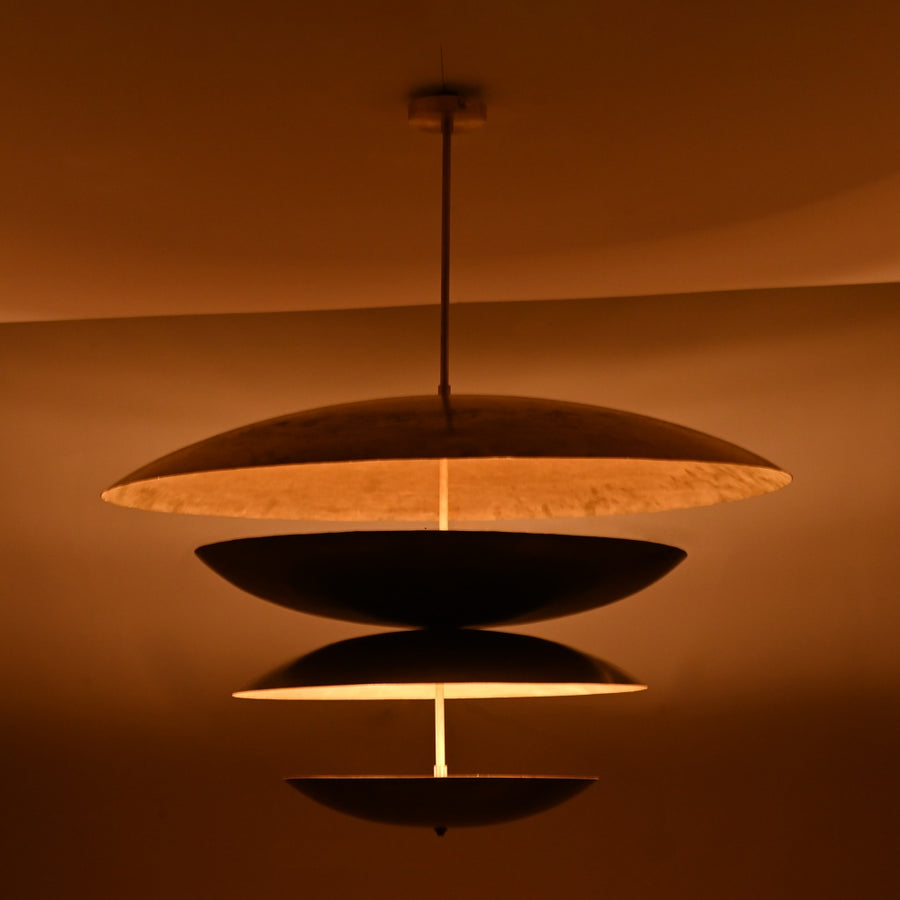 Modern sculptural brass chandelier featuring stacked black and gold discs crafted in a unique layered floating design.