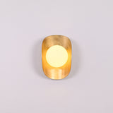 Brass shield globe sconce creating soft warm glow for luxury home and boutique interiors