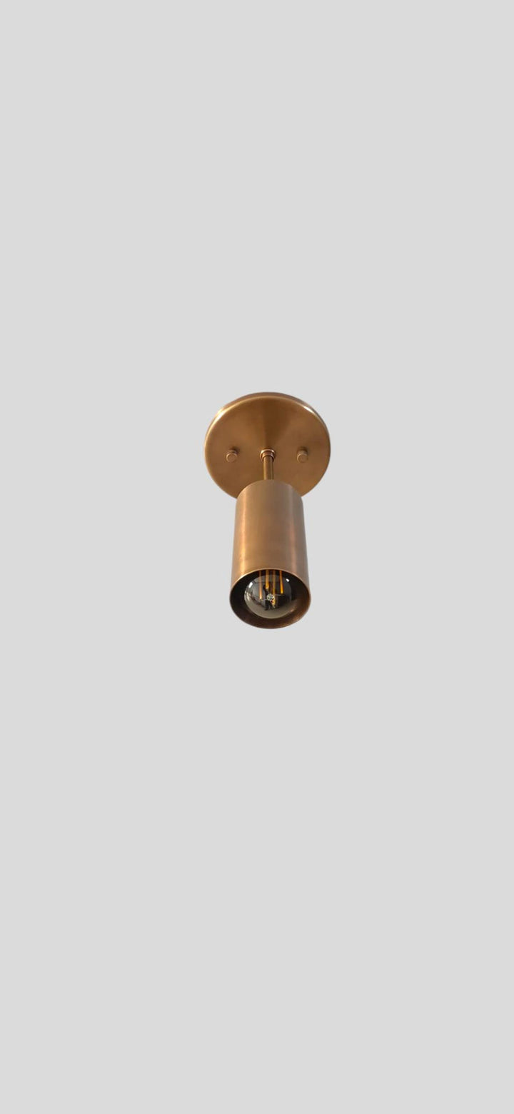 Bottom view of handcrafted brass spotlight with visible filament bulb and smooth lacquer-coated finish