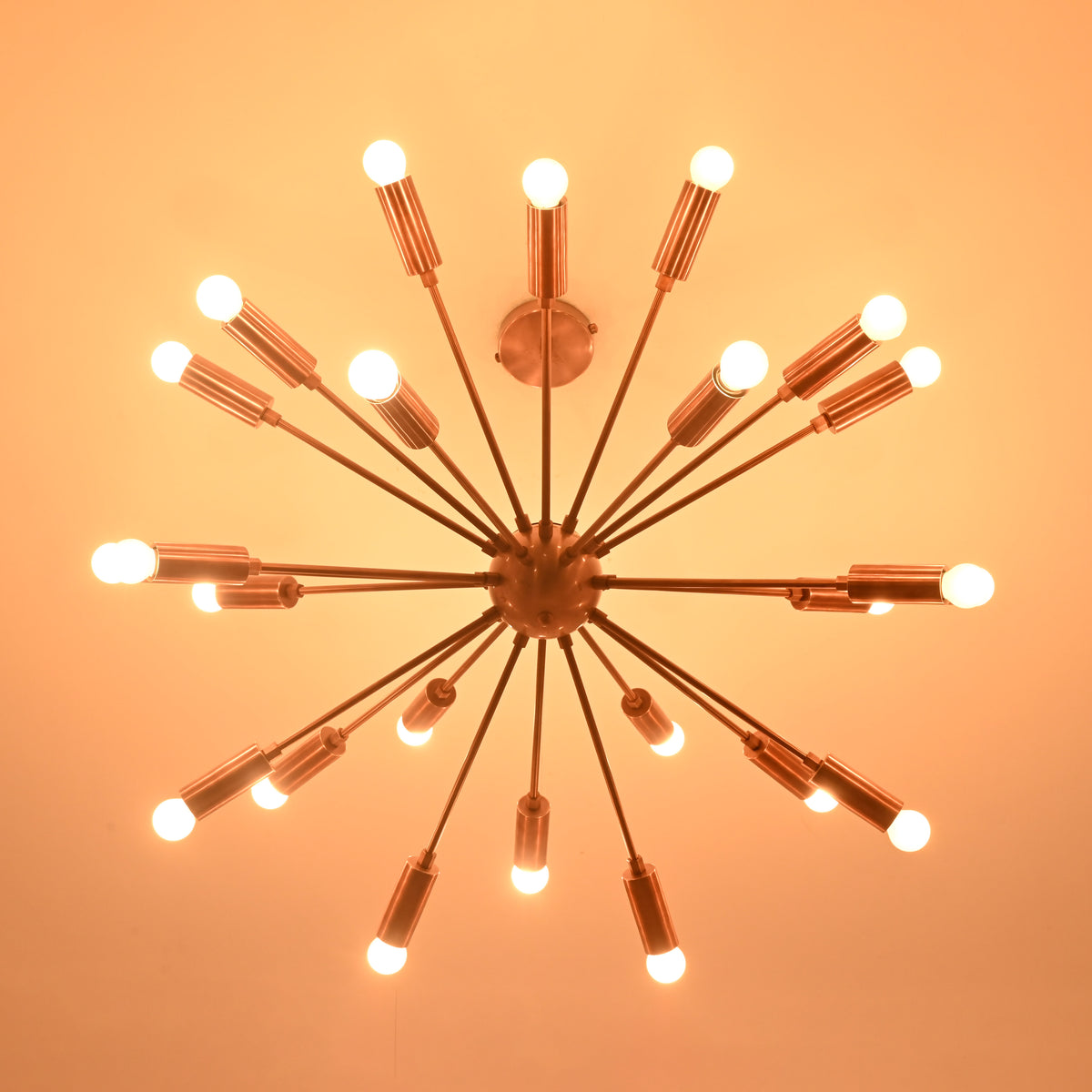 Bottom view of brass sputnik chandelier illuminated in dark setting with soft warm light.