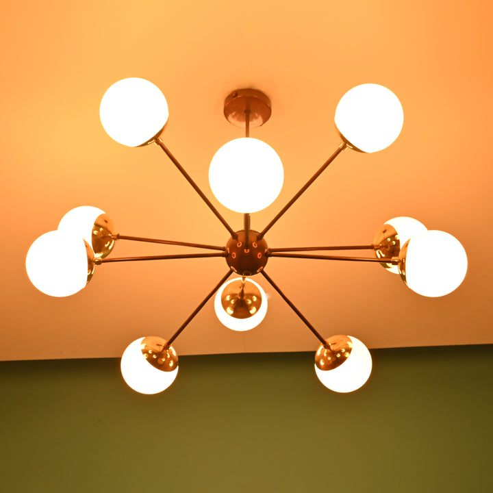 Brass Sputnik chandelier bottom view showing even light glow from opal glass globes against a warm background.