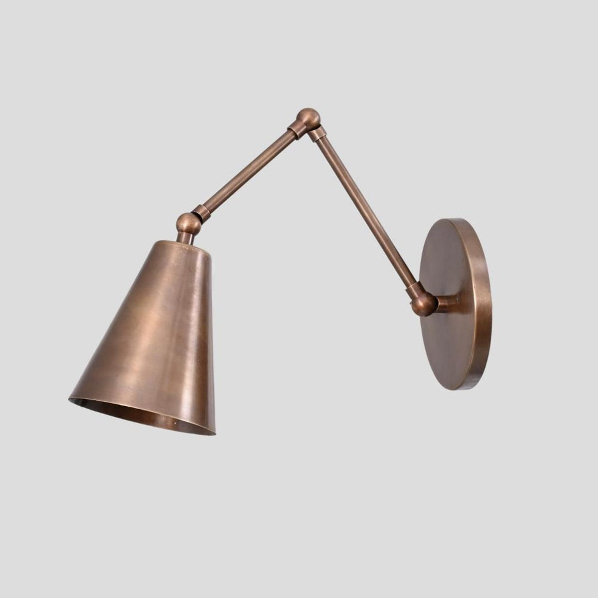 Industrial style brass wall lamp with pivot arm and cone shade for modern interiors