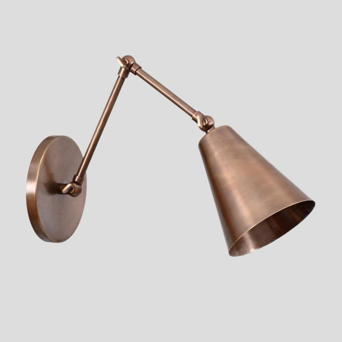Solid brass adjustable wall lamp with conical shade, ideal for bedroom or living room lighting