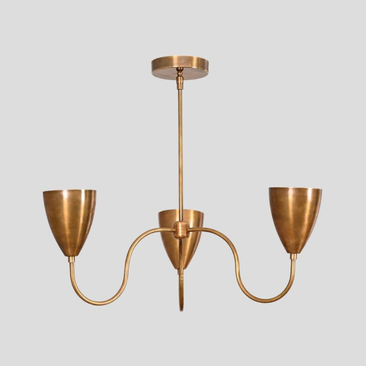 Straight front view of handcrafted brass chandelier with three conical shades, minimalist industrial ceiling lighting fixture.