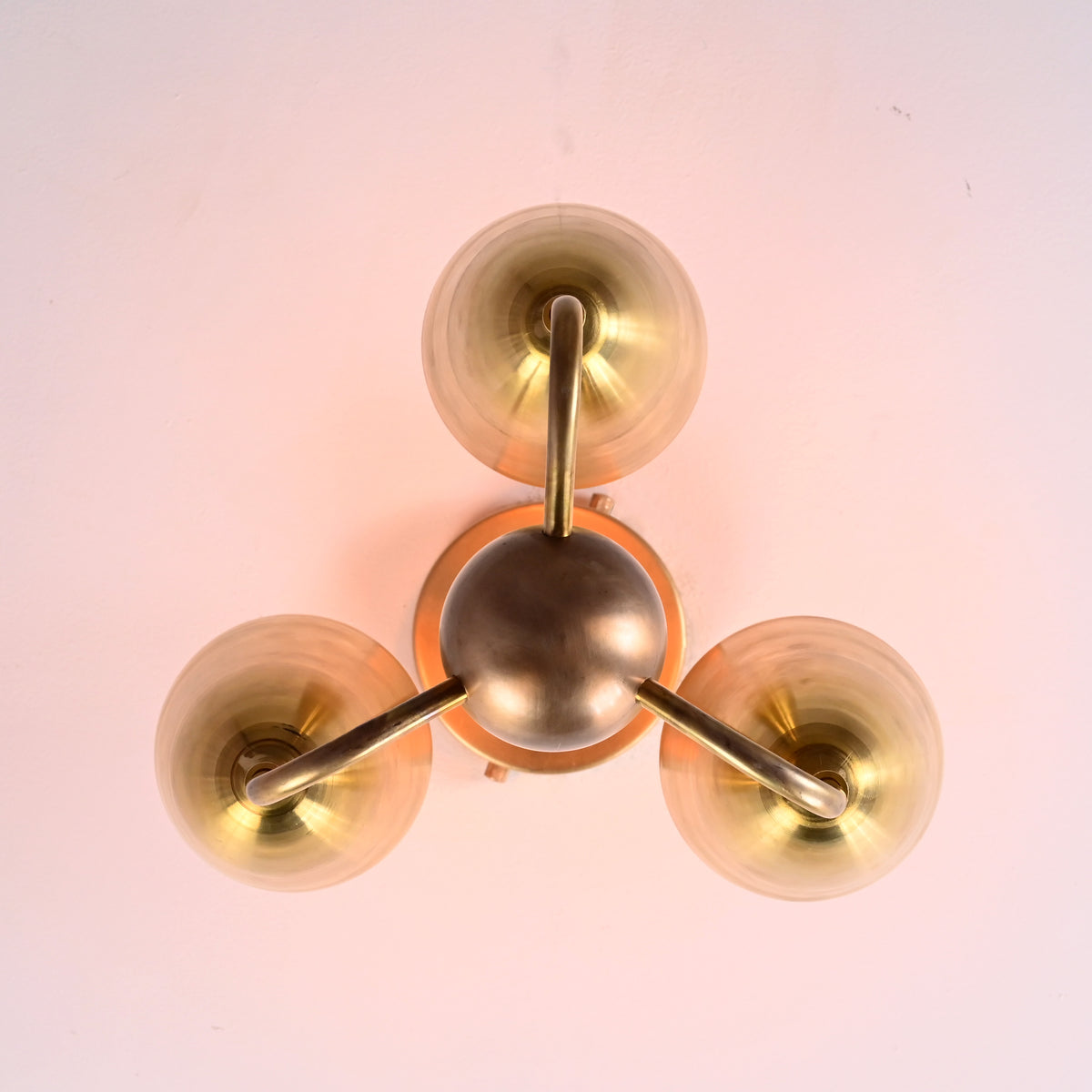 Top-down view of brass triple cup light showing circular geometry and refined brass detailing.