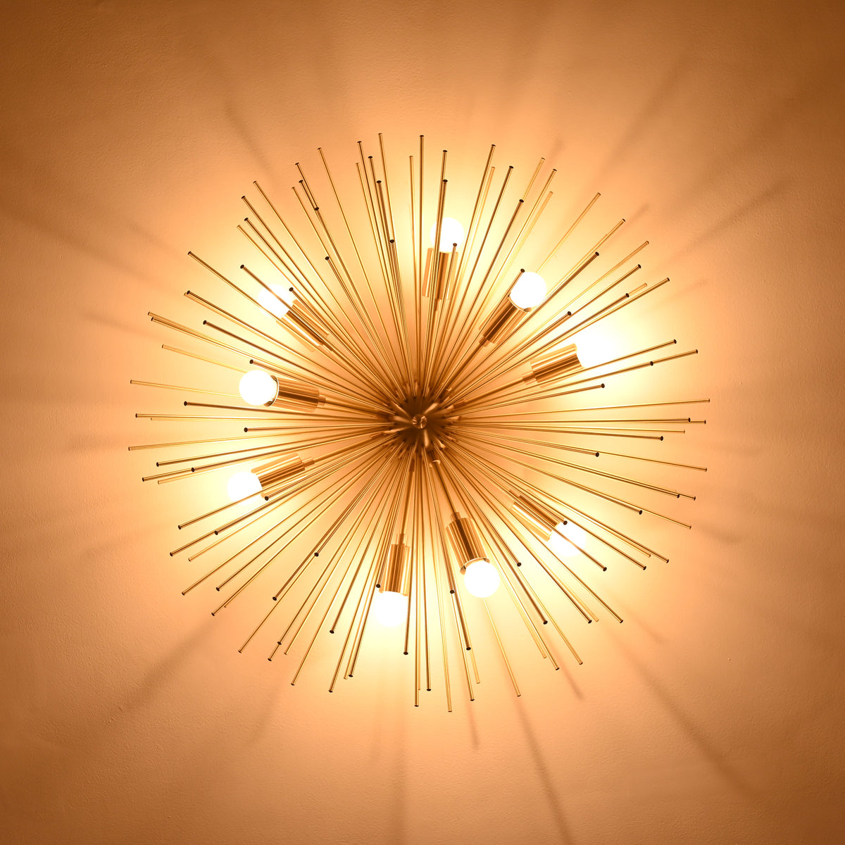 Bottom view of illuminated brass urchin ceiling light creating soft radial shadows on the ceiling.