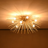 Brass urchin chandelier lit in a dark room, casting dramatic warm light patterns across the ceiling.