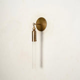 Slim vertical brass wall sconce with frosted glass tube shade, industrial modern wall light angled side view