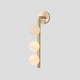 Vertical brass wall sconce featuring three frosted globe lights, minimalist modern lighting design
