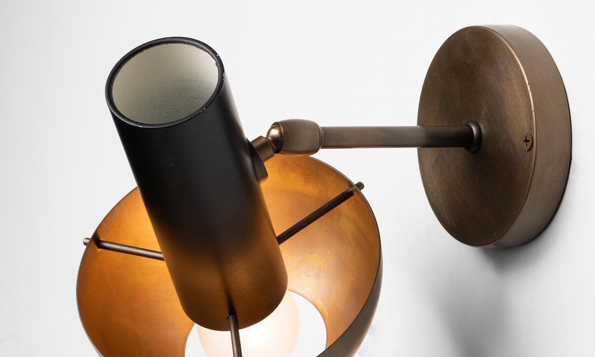 Angled detail of modern brass wall lamp showcasing bowl shade, inner glow, and precision-crafted brass hardware.